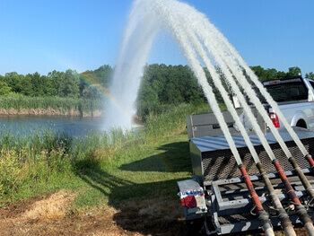 View of truck inspecting fire pump fed by pond 